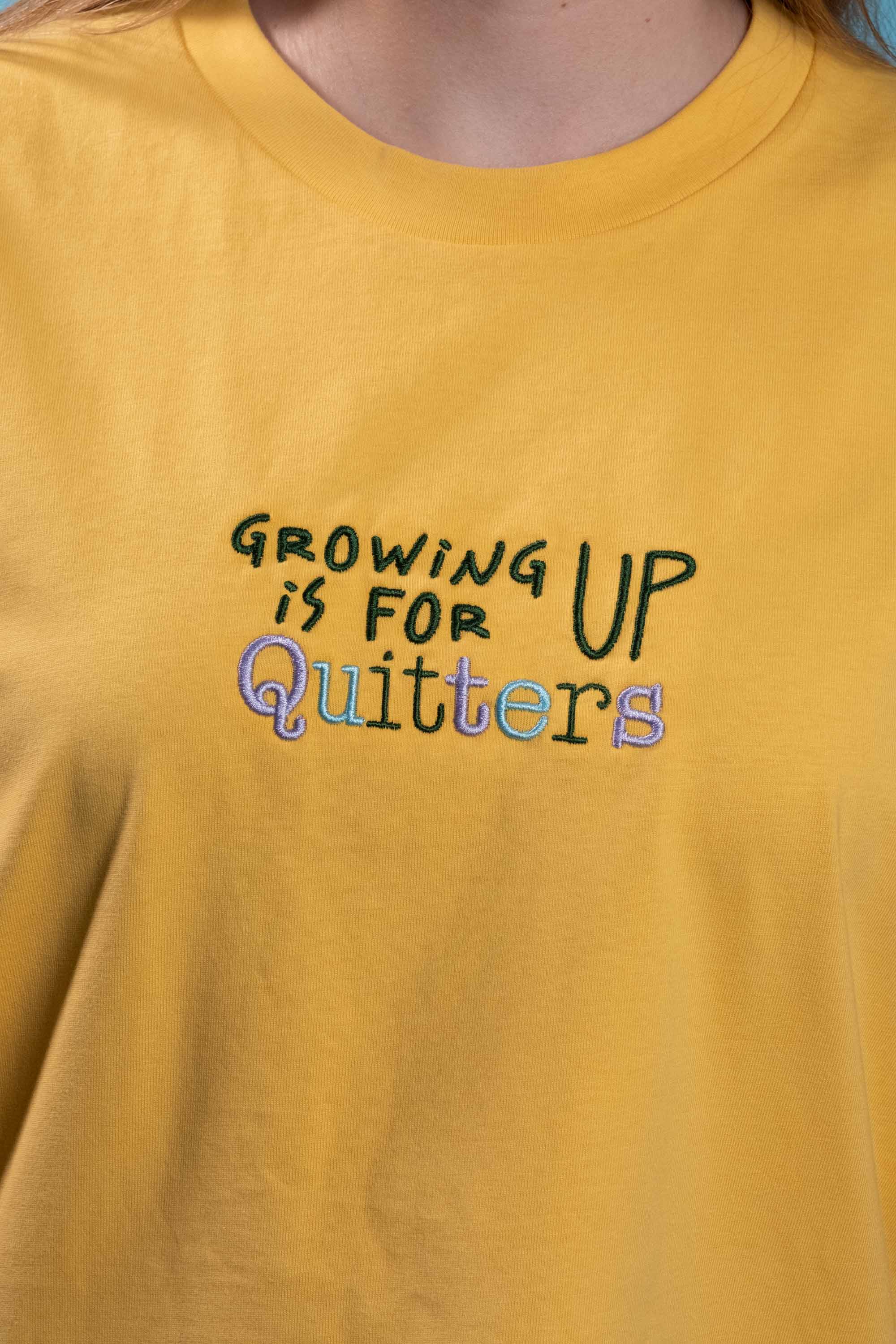 Preshrunk yellow cotton t-shirt with 'growing up is for quitters' embroidered design